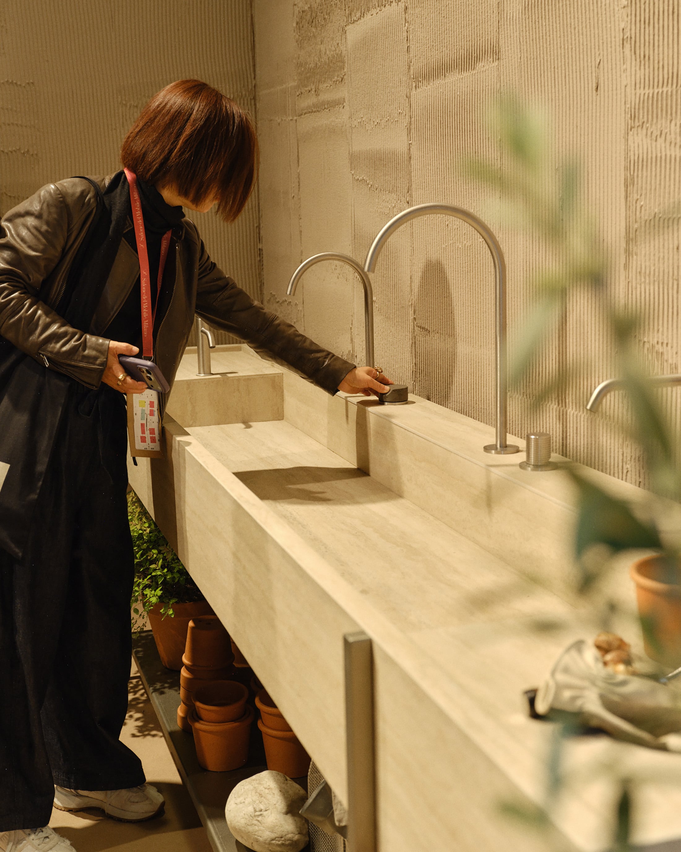 Woman trying out a bathroom tap handle in a graden setting