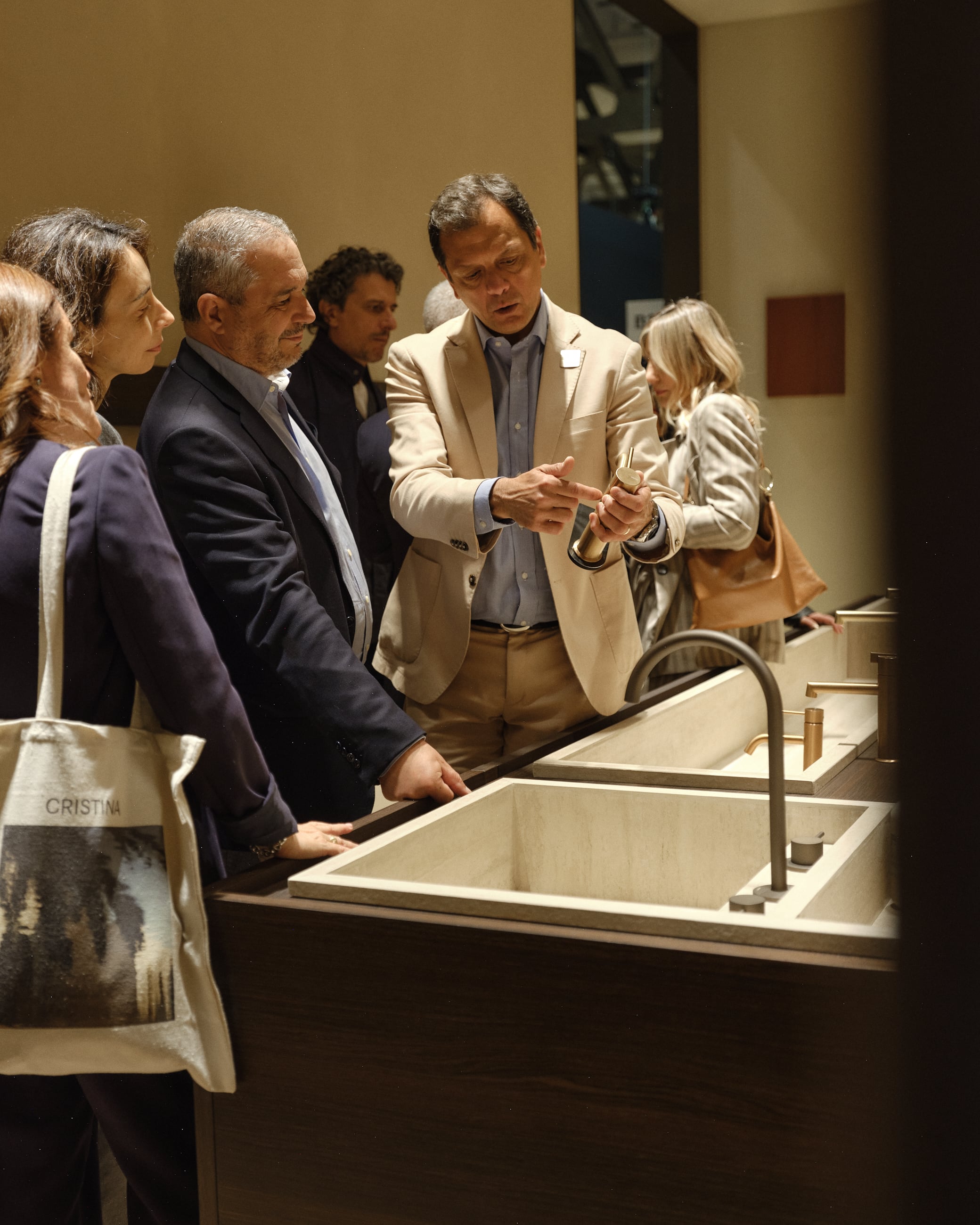Man explaining a brass bathroom tap to a group of people